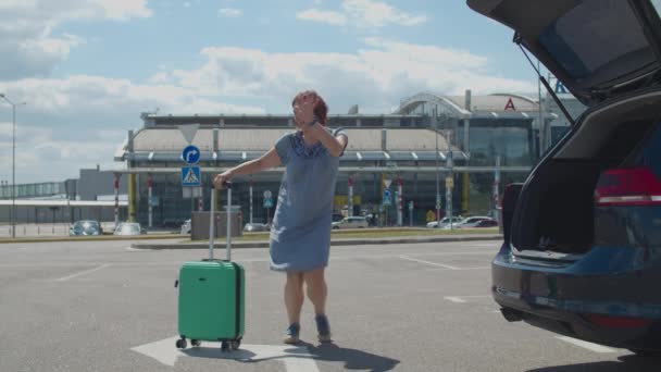 Jovem mulher feliz dançando sozinha com mala perto do prédio do aeroporto. turista feminino está feliz em viajar. Excitada senhora pulando e dançando . — Vídeo de Stock