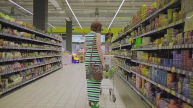 30 'lu yaşlardaki koruyucu maskeli bir kadın süpermarkette market alışverişi yapıyor. Karantina alışverişi.