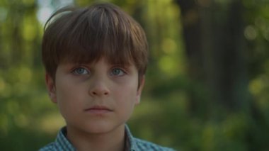 Otistik çocuk portresi dışarıda. Okul çocuğu yazın şehir parkında dikiliyor. Düşünceli çocuk portresi.