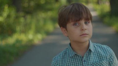 Dışarıda çocuk portresi var. Okul çocuğu yazın şehir parkında dikiliyor. Düşünceli çocuk portresi.