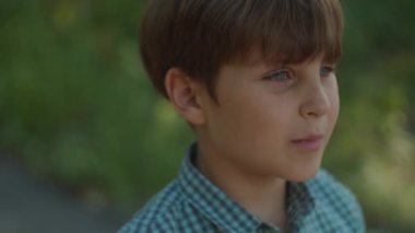 Otistik çocuk portresi dışarıda. Okul çocuğu yazın şehir parkında dikiliyor. Düşünceli çocuk portresi.