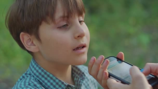 Een schooljongen die moeder sms 't terwijl ze haar hand vasthoudt. Mam schenkt geen aandacht aan zoon. Kind probeert mobiele telefoon uit moeders handen te nemen. — Stockvideo