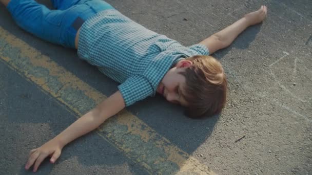 Az iskolás fiú a park ösvényén pihen. Autista fiú feküdt a földön, széttárt karokkal.. — Stock videók