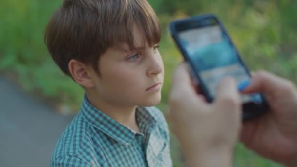 Skolpojken tittar på när mamma sms:ar på mobilen med handen. Mamma bryr sig inte om sin son. Ungen försöker ta mobilen ur mammas händer. — Stockvideo