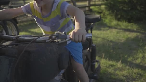 Niño preescolar jugando con una vieja motocicleta afuera. El niño finge andar en moto. Vehículo antiguo en el parque. — Vídeos de Stock