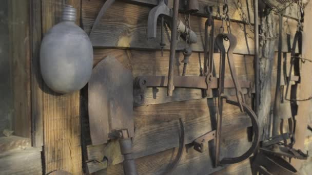 Zastaralé rezavé lovecké vybavení na dřevěné stěně. Staré pasti, lopata atd. venku. — Stock video