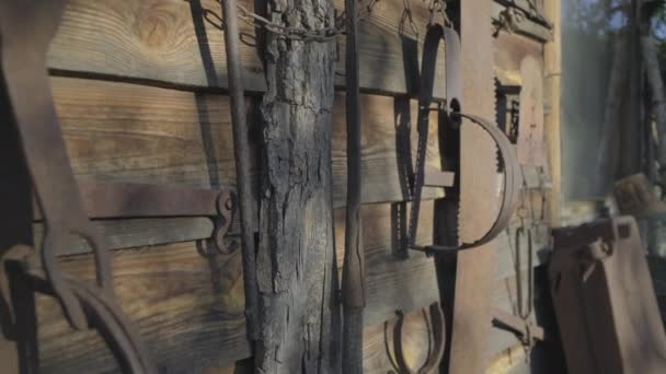 Verouderde roestige jachtuitrusting op de houten muur. Oude vallen, schep enz., buiten. — Stockvideo
