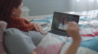 Yatakta yatan hasta genç bir kadın doktora danışmanlık yapıyor. İnternette doktorla konuşurken kadın öksürüyor ve burnunu siliyor. Grip ve diğer virüs hastalıkları. Çevrimiçi doktor danışmanlığı.