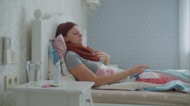 Hasta genç bir kadın öksürüyor, burnunu siliyor ve evde yatarken burun spreyi kullanıyor. Kadınlar mevsimsel virüs hastalığından muzdarip..
