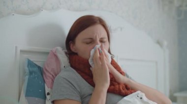 30 'lu yaşlardaki genç bir kadın burnunu peçeteyle silip grip ya da evdeki solunum virüsleri gibi hastalıkların tedavisi için astım spreyi kullanıyor. Kadın öksürük ilacı solunum cihazıyla tedavi ediliyor..