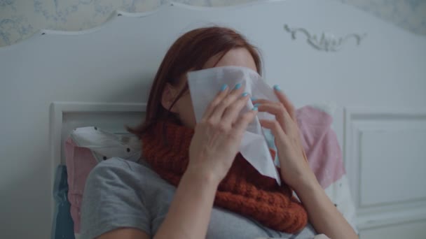 Sick young woman coughs, blows her nose and uses nasal spray laying in bed at home. Woman suffers from seasonal virus disease. — Stock Video