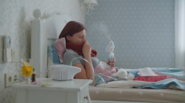 30 'lu yaşlardaki genç bir kadın burnunu peçeteyle silip grip ya da evdeki solunum virüsleri gibi hastalıkların tedavisi için astım spreyi kullanıyor. Kadın öksürük ilacı solunum cihazıyla tedavi ediliyor..