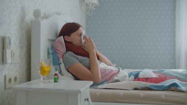 Больной молодой женщины кашляет, сморкается и использует носовые капли в носу, лежащие в постели дома. Женщина страдает от сезонных вирусных заболеваний, таких как грипп. — стоковое видео