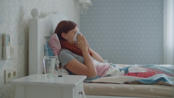 Beteg fiatal nő köhög, orrát fújja, és orvosságot csöpög az ágyban heverő vízbe. A nő szenved szezonális vírus betegség, mint az influenza. — Stock videók