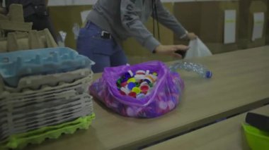 30 'lu yaşlardaki koruyucu maskeli genç bir kadın metal kutular, plastik ve cam şişeler gibi geri dönüşüm atıklarını sıralıyor. Çevreyi kurtarmak, plastik tüketimini azaltmak. Sıfır atık.
