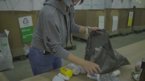 Mujer joven de 30 años en mascarilla protectora facial que clasifica los residuos de reciclaje como latas de metal, botellas de plástico y vidrio. Ahorre ambiente, reduzca el consumo de plástico. Concepto de cero residuos. — Vídeos de Stock