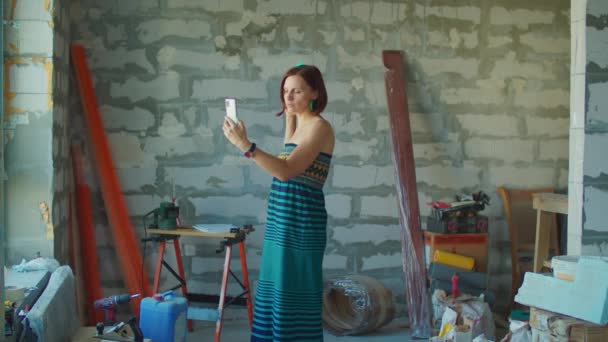 Mladá třicátnice mluví na mobilu prostřednictvím videohovoru na staveništi. Žena je šťastná s rekonstrukcí bytu a vzrušeně mluví se svým přítelem. — Stock video