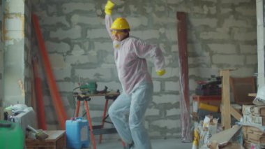 İnşaat alanında dans eden beyaz takım elbiseli komik kadın işçi. Pozitif ev yenileme işlemi. 