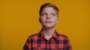 Genç bir çocuk başını arkaya eğiyor, geniş gözlerle bakıyor ve inançsızlık ifadesi sergiliyor. Parlak sarı arka plan onun şaşırmış ve şaşırmış tepkisini arttırır..