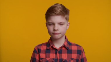 Genç bir çocuk başını bir aşağı bir yukarı sallayarak onay ya da mutabakat işareti veriyor. Parlak sarı arka plan, jestinin olumlu ve olumlu havasını arttırır..
