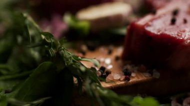 Taze yeşil otlar ve sebzelerle çevrili, tuzlanmış çiğ biftek. Barbekü, aşçılık ve gurme yemek içeriği için mükemmel.