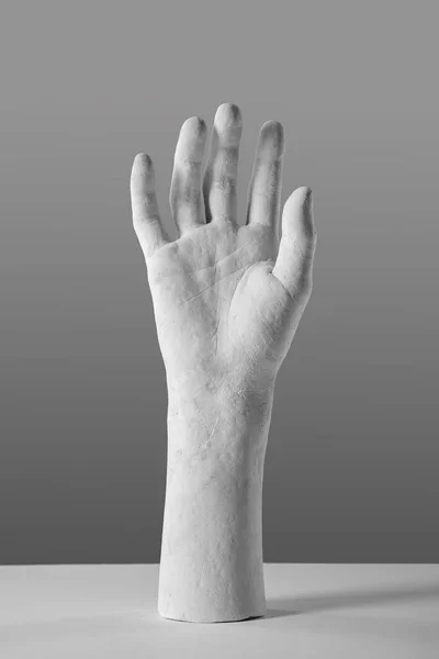 elegant white plaster hand on a gray background