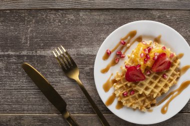 waffles with strawberries on a white plate on a white background with golden fork and knife clipart