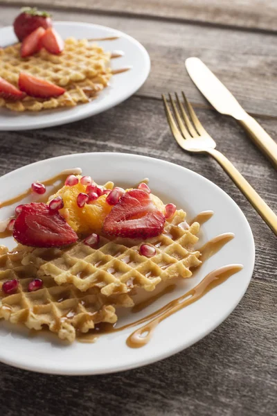 altın çatal ve bıçak ile beyaz bir arka plan üzerinde beyaz bir tabak üzerinde çilek ile waffle