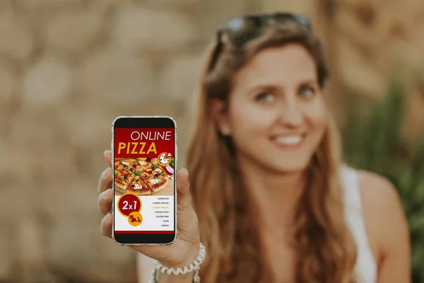 Woman holding and showing a mobile phone with online pizza delivery service