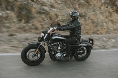Adam siyah giysili bir siyah klasik Amerikan motosiklet Binme 