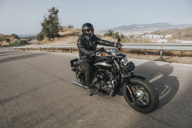Adam siyah giysili bir siyah klasik Amerikan motosiklet Binme 