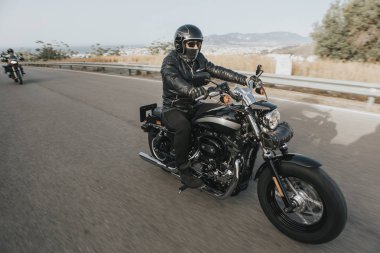 Adam siyah giysili bir siyah klasik Amerikan motosiklet Binme 