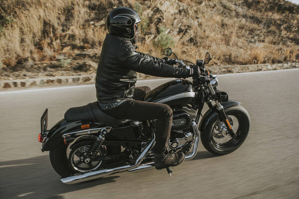 Side view of classic motorbike rider riding an American classic motorcycle