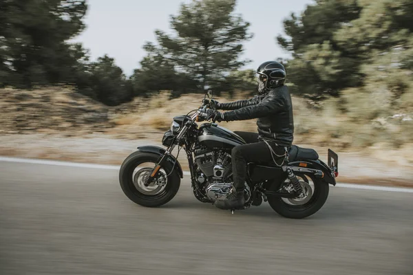 Bir motosiklet sürme yolda dağ arasında siyah deri ceketli adamı.