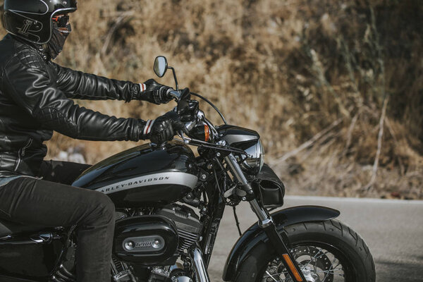 Malaga, Spain - July 15, 2018: Man riding his Harley Davidson motorcycle during a journey trip around Malaga mountain roads in Spain.