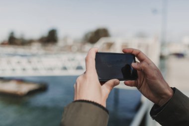 Tatil sırasında bir resim çekmek için bir cep telefonu tutan adam el yakın çekim.
