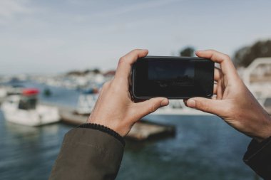 Tatil sırasında bir resim çekmek için bir cep telefonu tutan adam el yakın çekim.