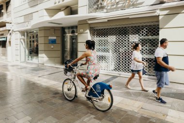 Malaga, İspanya - 2 Eylül 2018: Malaga, İspanya'nın şehir merkezinde bir yolculuk sırasında bir bisiklet sürme kadın.