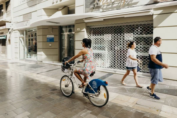 Malaga, İspanya - 2 Eylül 2018: Malaga, İspanya'nın şehir merkezinde bir yolculuk sırasında bir bisiklet sürme kadın.