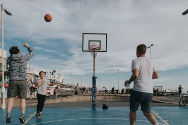 Brighton, İngiltere - 24 Ekim 2018: Brighton beach promenade, gün batımında yerleştirilen mahkemeler basketbol oynayan gençler.