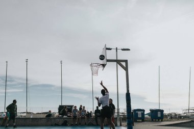 Brighton, İngiltere - 24 Ekim 2018: Brighton beach promenade, gün batımında yerleştirilen mahkemeler basketbol oynayan gençler.