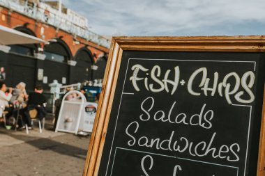 Blackboard restoran menü ve bilgi bir mesire ortasında, balık ve patates kızartması, salata, sandviç ve diğer gıda ile.