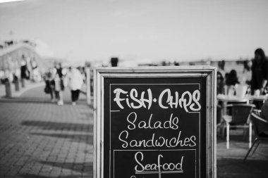 Blackboard restoran menü ve bilgi bir mesire ortasında, balık ve patates kızartması, salata, sandviç ve diğer gıda ile.