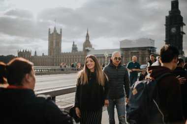 Londra, İngiltere - 25 Ekim, 2018: mutlu çift Westminster Sarayı ve arka planda, Londra, İngiltere'de Big Ben ile Westminster Bridge kaldırım tarafından yürüyüş.