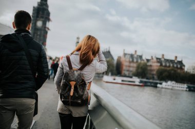 Londra, İngiltere - 25 Ekim, 2018: Thames Nehri ve Londra, İngiltere arka planda Big Ben ile Westminster Bridge tarafından yürüyüş onların sırt içinde genç çift.
