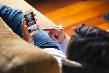 Bir seyahat acentası yalan sırasında aşağı evde Web sitesi için bir cep telefonu tutan kadın.