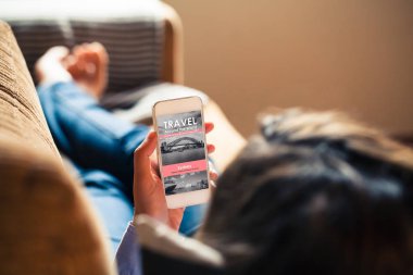 Bir seyahat haber sitesi evde okumak için bir cep telefonu tutan kadın.