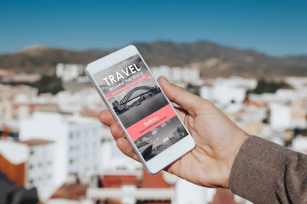男子手拿着手机 旅游新闻网站在屏幕上 有城市背景 — 图库照片