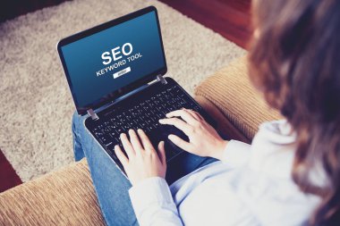 Evde kanepede otururken bir Web sitesi Seo konumlandırma yapmak için bir dizüstü bilgisayar kullanan kadın.
