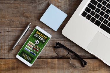 Ofis masası ve hareket eden telefon ekranında spor bettinhg Web sitesi ile üstten görünüm.